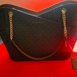 MK JET SET TRAVEL. BROWN LG X CHN SHOULDER TOTE